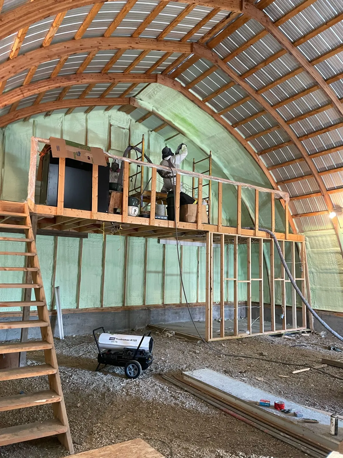 Large farm building with walls and ceiling being sprayed from a lift